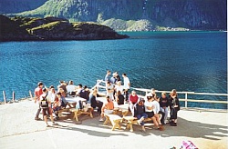 Participants of a youth group gathered on the seahouse quay where Steinfjorden stretches out its left arm Maervollpollen. In the background the giant seaalps Himmeltindene (the Heaven Peaks).