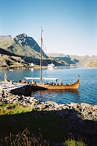 The Viking ship Lofotr, Skarvhellodden. Behind the ship the spacious white seahouse Joh. L. Unstad Sjohus at Maervollpollen, the northern continuation of the fjord Steinfjorden. Reception in the white house (No.205) above the seahouse.